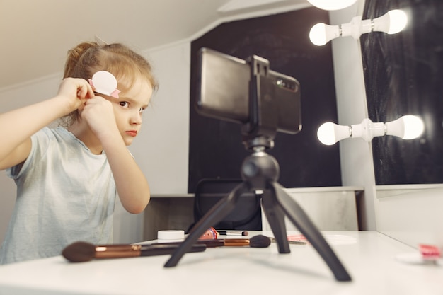 Mignon petit blogueur avec des cosmétiques d'enregistrement vidéo à la maison