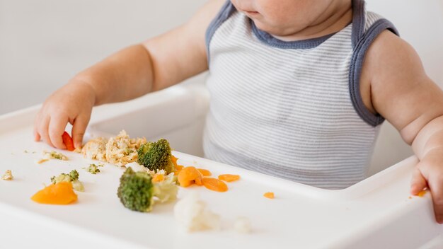 Mignon petit garçon en chaise haute en choisissant quoi manger