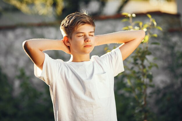 Mignon petit garçon dans un jardin. Enfant dans un t-shirt blanc.