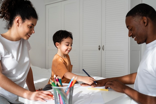 Photo gratuite mignon petit garçon dessinant la main de son père sur papier en souriant