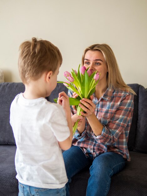 Mignon petit garçon donnant à sa mère des fleurs