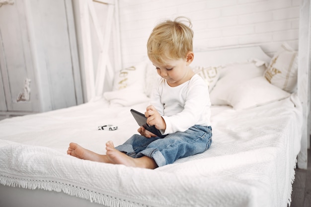 Mignon petit garçon jouant avec un ordinateur portable sur un lit