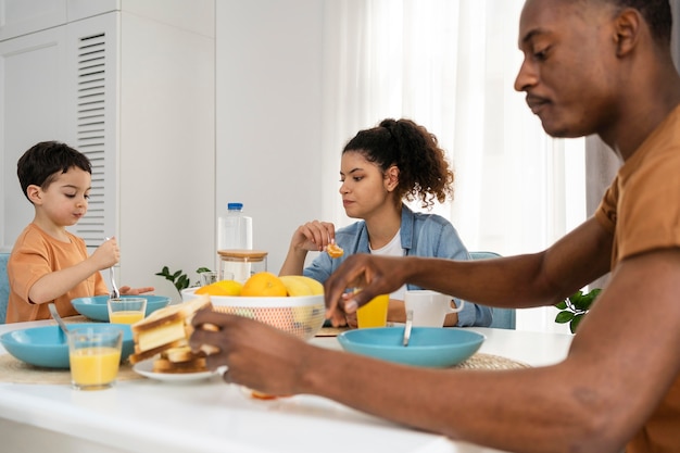 Mignon petit garçon prenant son petit déjeuner avec ses parents