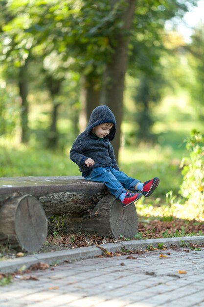 Mignon petit garçon reposant sur un banc en bois
