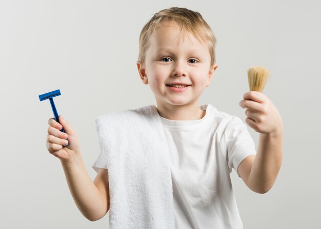 Mignon, sourire, petit garçon, tenue, rasoir, et, blaireau, tenir contre, fond blanc