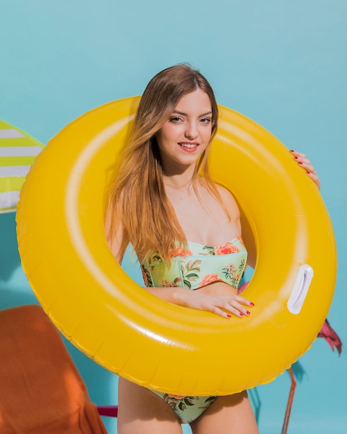 Mignonne jeune femme debout dans un cercle de nage en studio
