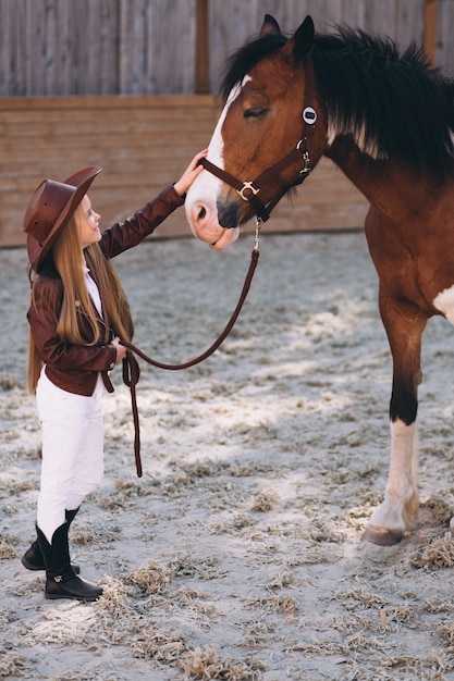 Photo gratuite mignonne petite fille blonde avec un cheval au ranch