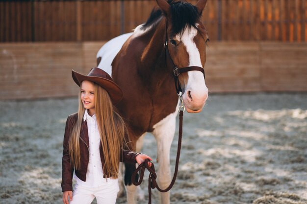Mignonne petite fille blonde avec un cheval au ranch