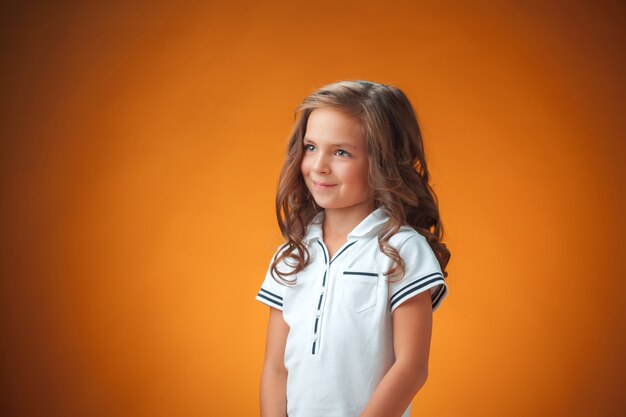 La mignonne petite fille joyeuse sur fond orange