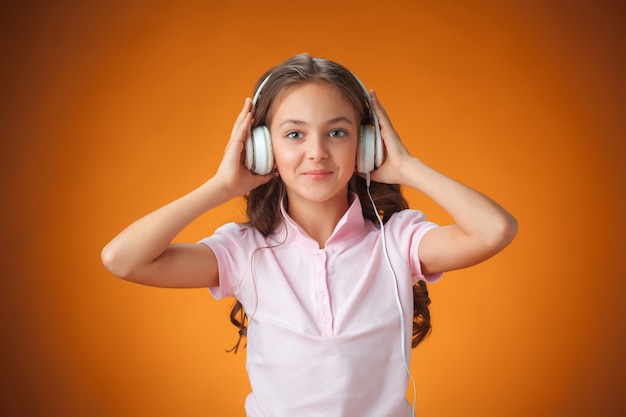 La mignonne petite fille joyeuse sur le mur orange