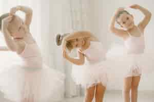 Photo gratuite mignonnes petites ballerines en costume de ballet rose. les enfants dans une pointe danse dans la salle