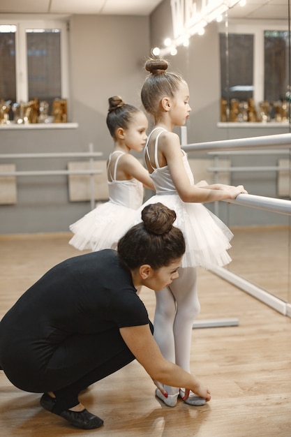 Photo gratuite mignonnes petites ballerines en costume de ballet rose. les enfants en pointes dansent dans la salle. enfant en cours de danse avec professeur.