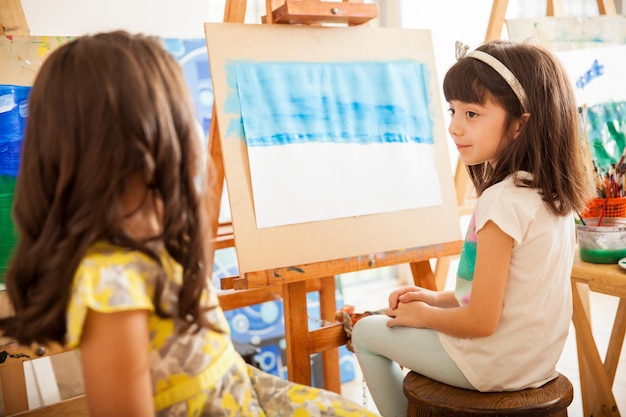 Photo gratuite mignonnes petites filles comparant le travail de l'autre et partageant des idées pour son cours d'art à l'école