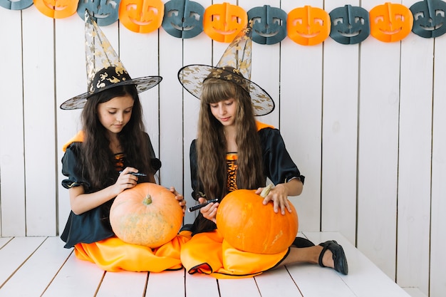 Photo gratuite mignonnes sorcières d'halloween tirant sur des citrouilles