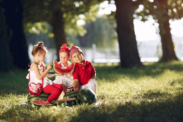 Mignons petits enfants avec des pastèques dans un parc