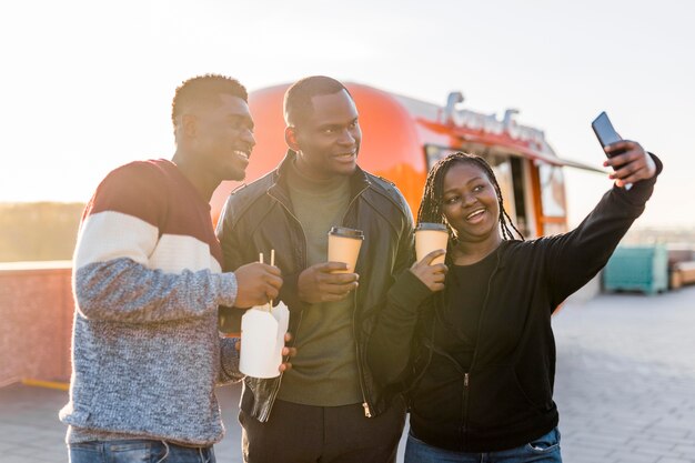 Milieu shot amis près de camion alimentaire prenant selfie