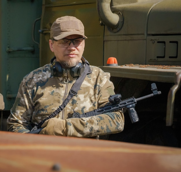 Un militaire ukrainien monte la garde avec une arme dans les mains pour protéger les civils Un homme portant des munitions militaires monte la garde