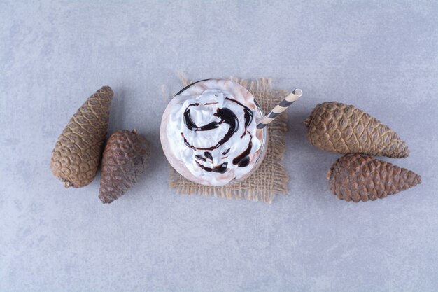 Milkshake au chocolat avec crème fouettée et pomme de pin sur table en marbre.