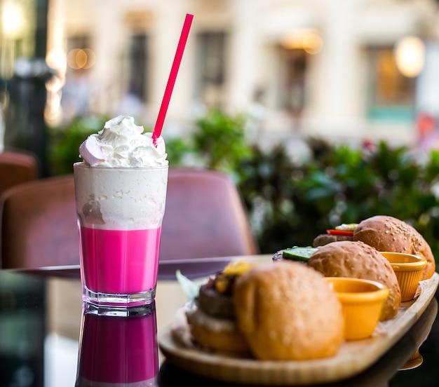 Milkshake vue latérale avec crème fouettée et hamburgers