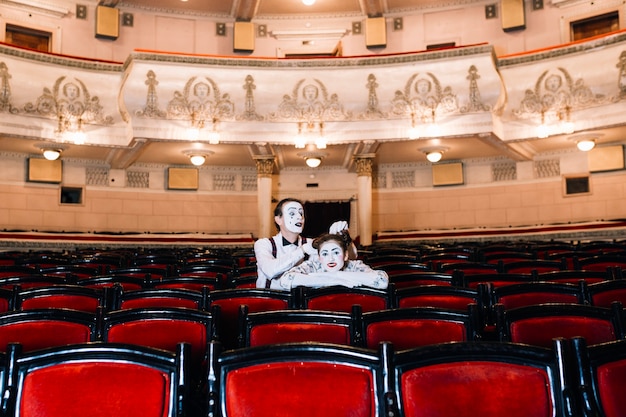 Mime artiste masculin jouant avec les cheveux de femme mime assis ensemble sur une chaise dans l&#39;auditorium