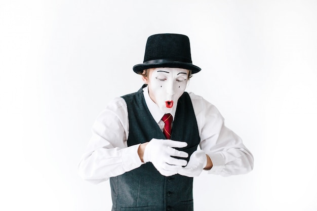 Mime drôle dans un chapeau noir regarde quelque chose d&#39;invisible dans ses bras