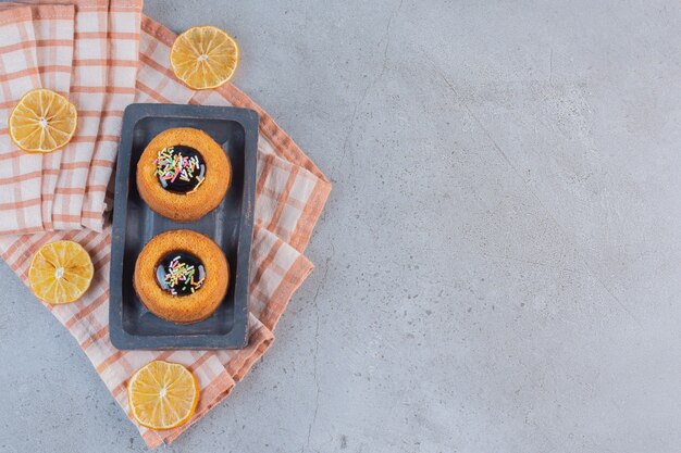 Mini gâteaux avec gelée et tranches de fruits sur table en pierre.