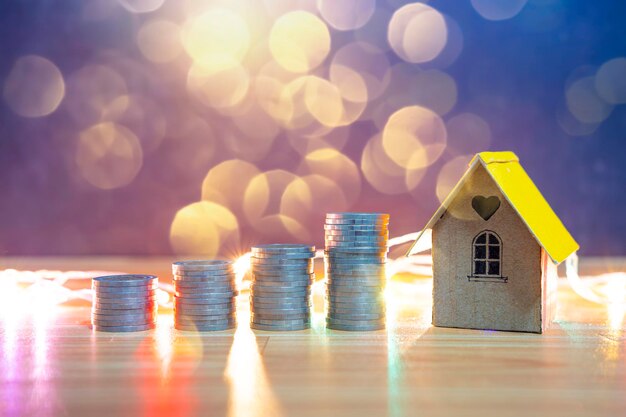 Mini maison sur pile de pièces concept d'immeuble de placement risque d'investissement et incertitude sur le marché du logement immobilier