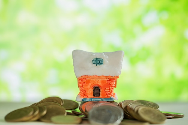 Photo gratuite mini maison sur pile de pièces avec flou vert.