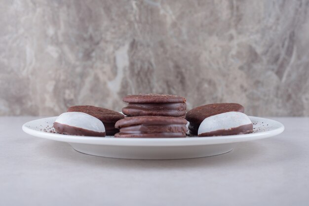 Mini pâtisserie mousse et biscuit enrobé de cholate dessert sur une assiette sur une table en marbre.