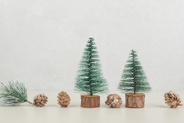 Mini sapins de Noël et pommes de pin sur surface beige