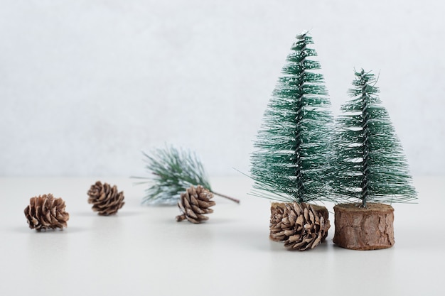 Mini sapins de Noël et pommes de pin sur surface beige