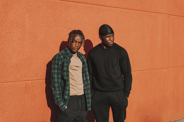 Mise au point peu profonde de deux hommes noirs debout contre un mur rouge