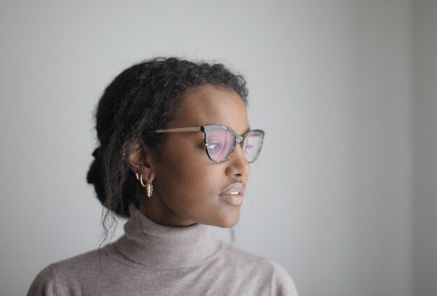 Mise au point peu profonde d'une femme afro-américaine avec des lunettes portant un col roulé gris