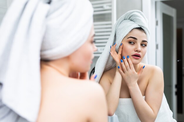 mise au point sélective de la belle jeune femme souriante touchant le visage tout en regardant le miroir