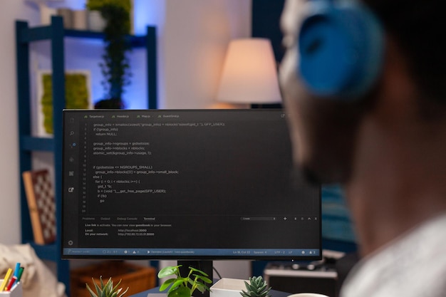 Photo gratuite mise au point sélective sur un employé informatique afro-américain avec un casque travaillant à distance depuis la maison lors de la conception de sites web à l'aide de technologies de programmation sur ordinateur. l'homme programmeur codage serveur d'entreprise numérique