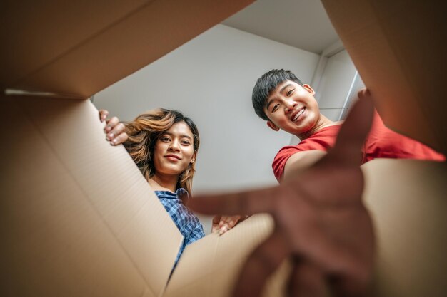 Mise au point sélective Heureux jeune couple ouvre le paquet et attrape quelque chose dans une boîte en carton Jeune couple dans le nouveau concept de maison