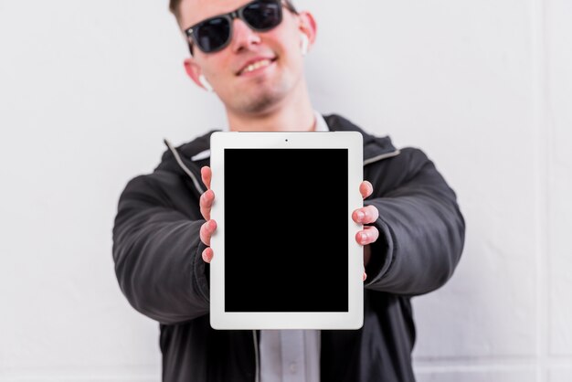 Mise au point sélective d&#39;un jeune homme montrant un écran de tablette numérique vierge à la caméra