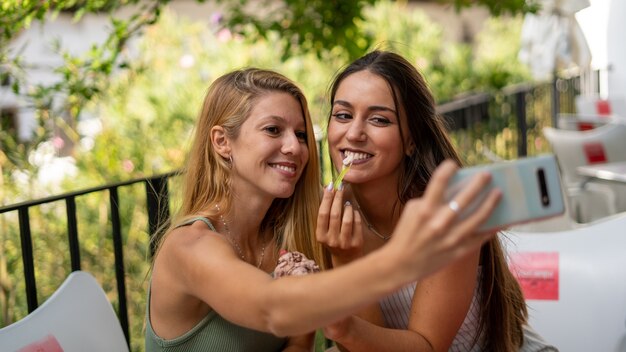 Mise au point sélective de jeunes filles séduisantes prenant un selfie dans un café