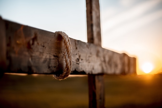 Mise au point sélective d'une main faite une croix en bois avec une corde enroulée autour et arrière-plan flou