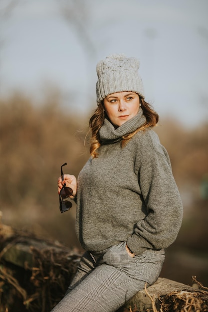 Mise au point sélective verticale d'une jeune femme portant un pull à col roulé gris, un pantalon et un chapeau