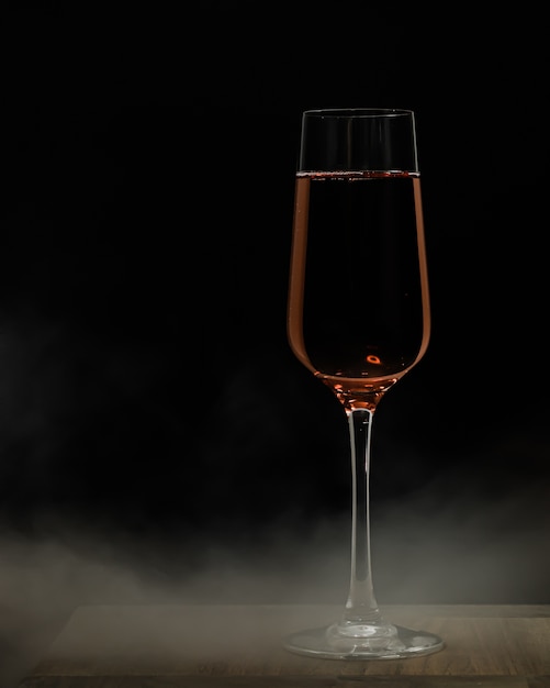 Mise au point sélective verticale tourné d'un verre de champagne sur une surface en bois et une distance noire