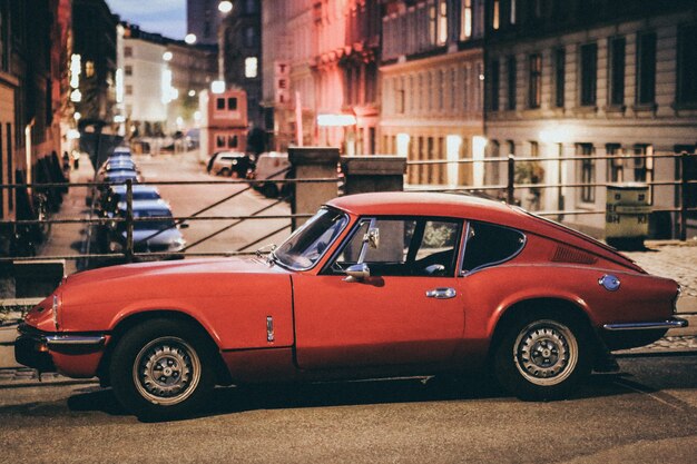 Mise au point sélective d'une voiture Porsche rouge garée près des bâtiments dans un arrière-plan flou