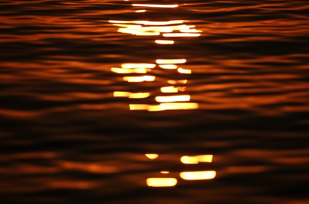 Photo gratuite mise au point de tir des vagues de la mer reflétant le soleil au coucher du soleil