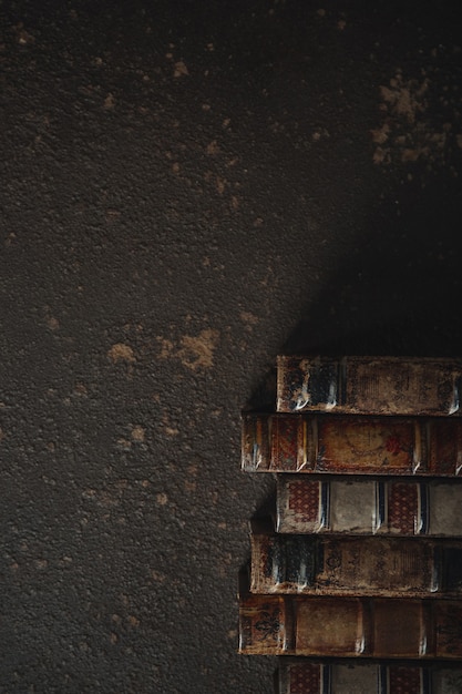 Mise à plat à l'ancienne avec pile de livres reliés en cuir antique contre un mur sombre