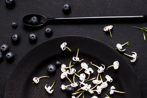 Mise à plat de bleuets sur une plaque sombre avec des fleurs