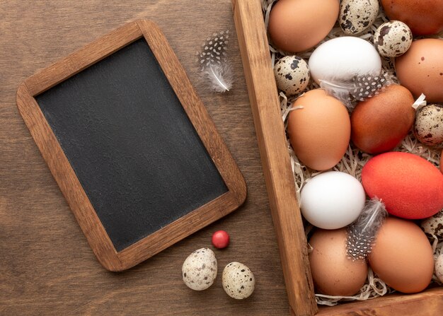 Mise à plat de boîte avec des oeufs pour Pâques et tableau noir