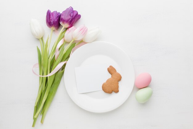 Mise à plat de bouquet de tulipes avec assiette et oeufs de Pâques colorés