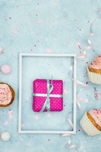 Photo gratuite mise à plat de cadeau d'anniversaire avec petits gâteaux et ruban