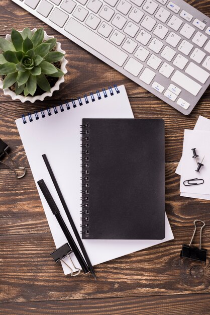 Mise à plat de cahier et clavier sur un bureau en bois avec succulentes