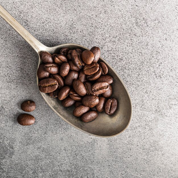 Mise à plat d'une cuillère en argent avec des grains de café